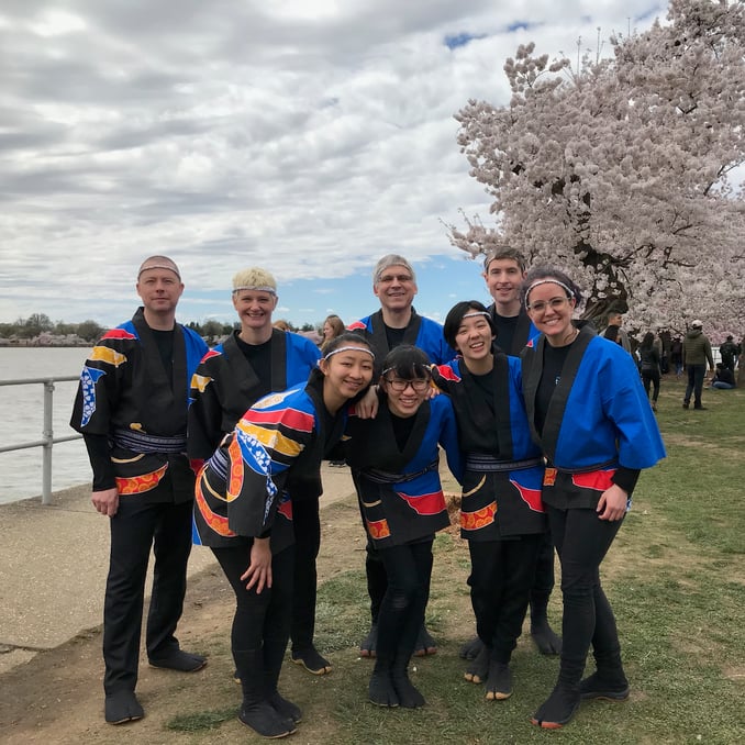 Group photo of Pittsburgh Taiko players at the Tidal basin with flowers in the background - from the 2019 show